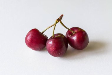 Bir sapta birkaç dut var. İhanet metaforu. Üçüncü tekerlek. İki ya da üç kiraz. Kırmızı meyveli vitaminler. Beyaz arka planda ürünler. Sağlıklı yaz meyveleri ve meyveleri.