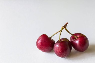 Bir sapta birkaç dut var. İhanet metaforu. Üçüncü tekerlek. İki ya da üç kiraz. Kırmızı meyveli vitaminler. Beyaz arka planda ürünler. Sağlıklı yaz meyveleri ve meyveleri.