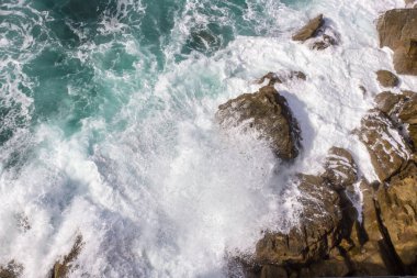 Biscay Körfezi. Doğanın öfkeli gücü. Dalgalar taşları yalıyor ve kayalara vuruyor. İspanyol sahilleri. Tuzlu deniz havası. Deniz dalgalarının püskürttüğü kaya ve taşlar. Yukarıdan deniz manzarası. Dalgaların sesi. Taş bir blokta dalgaların köpüğü.