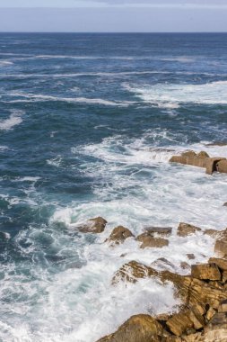 Biscay Körfezi. Doğanın öfkeli gücü. Dalgalar taşları yalıyor ve kayalara vuruyor. İspanyol sahilleri. Tuzlu deniz havası. Deniz dalgalarının püskürttüğü kaya ve taşlar. Yukarıdan deniz manzarası. Dalgaların sesi. Taş bir blokta dalgaların köpüğü.