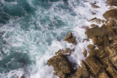 Biscay Körfezi. Doğanın öfkeli gücü. Dalgalar taşları yalıyor ve kayalara vuruyor. İspanyol sahilleri. Tuzlu deniz havası. Deniz dalgalarının püskürttüğü kaya ve taşlar. Yukarıdan deniz manzarası. Dalgaların sesi. Taş bir blokta dalgaların köpüğü.