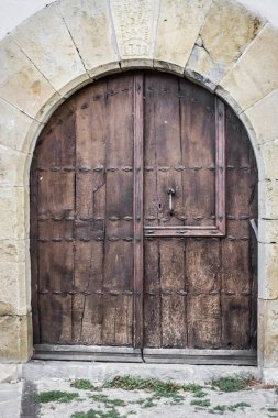 Ağır ahşap kapı. Taş bir binanın ön cephesinde antik bir kapı. Ortaçağ İspanya 'sının mimarisi. Pamplona sokakları. Katolik Kilisesi. Kilitli kocaman bir kapı..
