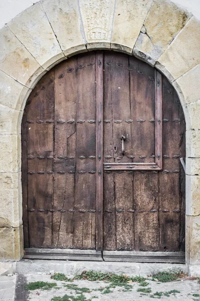 重い木製のドア 石造りの建物の正面にある古代の門 中世スペインの建築 パンプローナの通り カトリック教会 鍵付きの巨大なドア — ストック写真