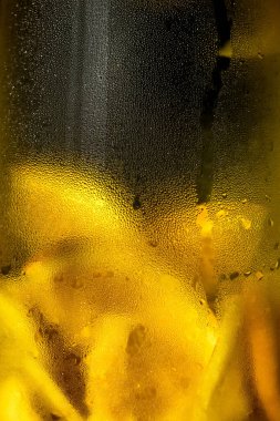 Soğuk limonata. Camda buhar var. Su damlaları yaklaşıyor. Vitamin içeceğini tazeliyorum. Limonlu soğuk su. Citrus meyvesi. C vitamini. Arka planda portakal meyvesi. Meyve sıçraması..