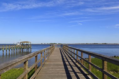 Wood boardwalk at Waterfront Park in Southport, North Carolina in the summer clipart
