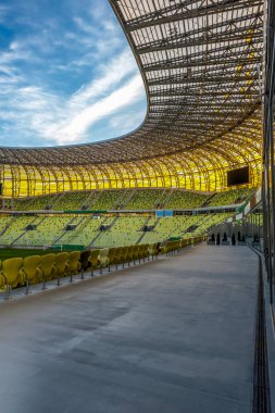Beyaz bulutlar ile açık stadyum çatı ve mavi gökyüzü. Bir arena veya stadyum kısmen açık bir çatı yapısı. Sarı koltuk