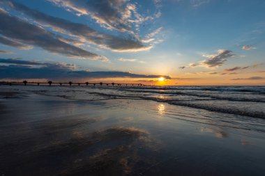 Güzel gün batımı Miedzyzdroje, sahilde bir arka planda büyük bir İskelesi, Güneş ve güzel gökyüzü yansıtılır, ıslak kum Polonya görebilirsiniz