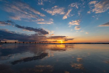 Güzel gün batımı Miedzyzdroje, sahilde bir arka planda büyük bir İskelesi, Güneş ve güzel gökyüzü yansıtılır, ıslak kum Polonya görebilirsiniz