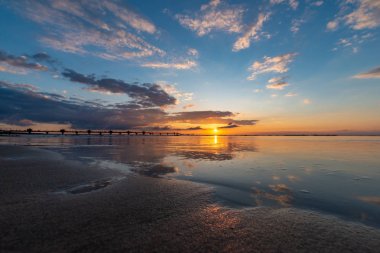 Güzel gün batımı Miedzyzdroje, sahilde bir arka planda büyük bir İskelesi, Güneş ve güzel gökyüzü yansıtılır, ıslak kum Polonya görebilirsiniz