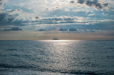 Güneş ışınları bulutları delip geçiyor. Uzakta aktif volkan Stromboli 'yi görebilirsiniz.