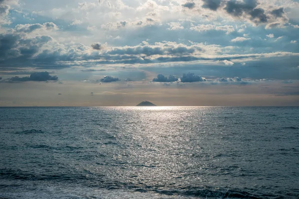 Güneş ışınları bulutları delip geçiyor. Uzakta aktif volkan Stromboli 'yi görebilirsiniz.