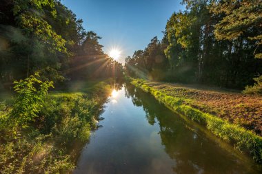Brda nehri kanalı, sakin su batan güneşin ışınlarını yansıtır, Bory Tucholskie, Polonya