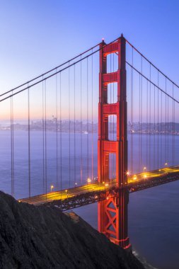 The north tower of the iconic Golden Gate Bridge stands tall backed by the city of San Francisco just before sunrise. clipart