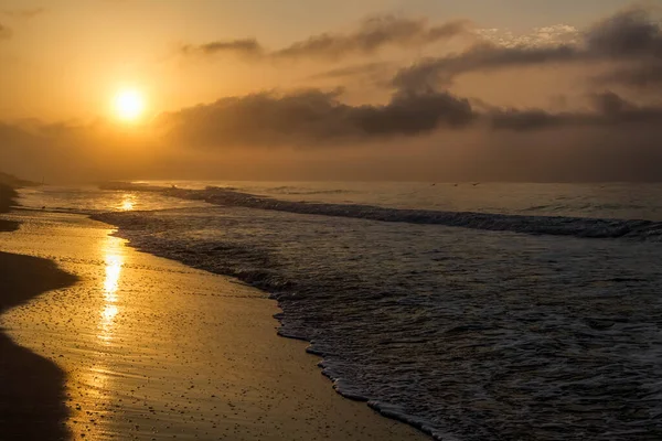 뉘엿뉘엿 넘어가는 알라바마 멕시코만 해안에는 황금빛 햇살이 비치고 있으며 해변과 스톡 사진