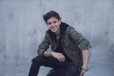 Yakışıklı genç adam oturuyor aşağı dışarıda somut adımlar güvenle gülümseyen