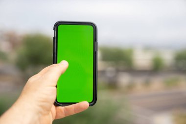 Yeşil ekran akıllı telefon ile açık arka plan bulanık tutan adam.