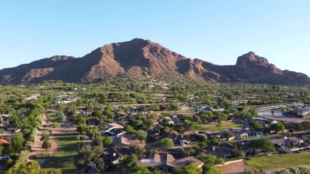 フェニックスアリゾナ州 黄金の時間の間に背景にキャメルバック山を囲むフェニックスの近所 住宅や公園の空中コミュニティドローンビュー — ストック動画