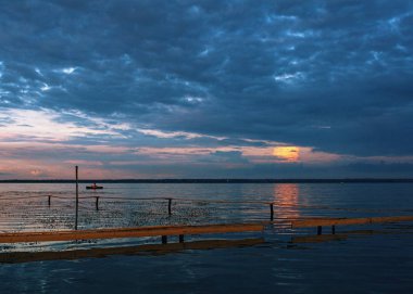 Ön planda insanlar balıkçılık ve ahşap iskele ile göl ve tekne de güzel gün batımı 