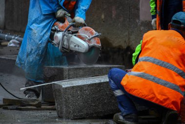 İşçiler caddenin onarımı sırasında yollar döşeme için dairesel testere taş bloklar ile testere