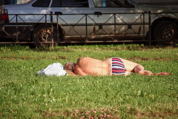 Man sleeps in shorts in the park on a sunny day — Stock Photo, Image