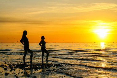 Denizde gün batımında iki kız siluetleri