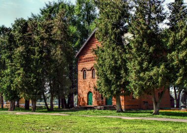 Güneşli bir yaz gününde yeşil parkta eski kilisenin Ortaçağ kırmızı tuğla bina