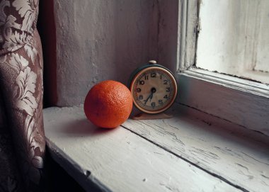 Beyaz ahşap penceredeki turuncu ve eski yeşil saatler zamanı 6: 35 olarak gösteriyor.