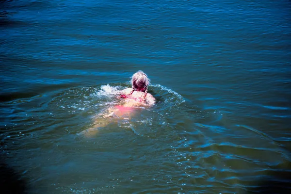 수영복을 소녀는 바다에서 헤엄치는 모습을 뒤에서 바라본다 — 스톡 사진
