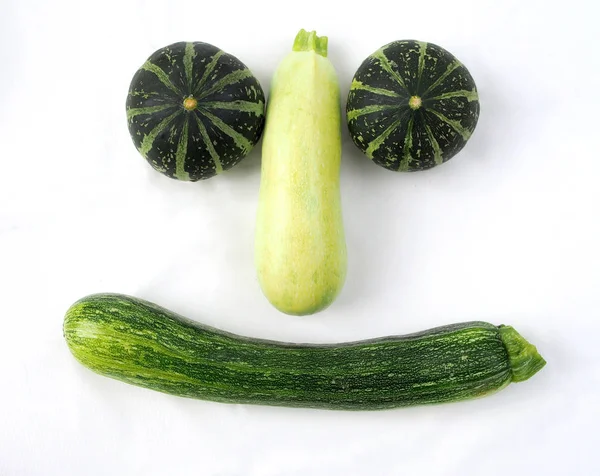 Small decorative green pumpkins and zucchini on a white background