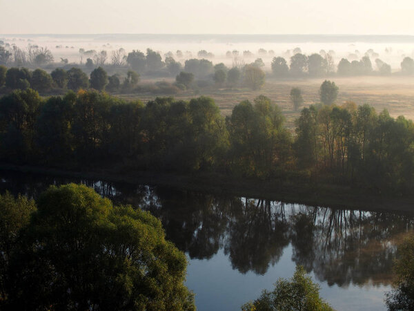 Top view of Desna River and meadows in fog in the early morning