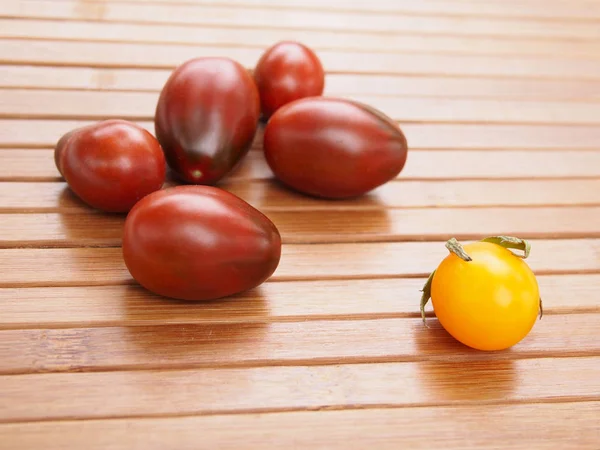 Beberapa Tomat Merah Gelap Dan Satu Kuning Permukaan Kayu — Stok Foto