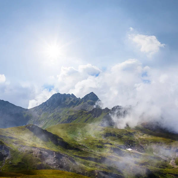 輝き太陽の下で密度の高い雲で緑の山脈 — ストック写真