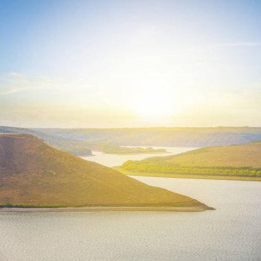 gün batımında yüksek bir sahil ile nehir