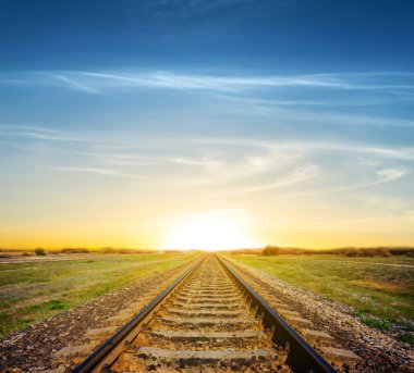 dramatik bir gün batımı için bir yeşil alanlar arasında demiryolu