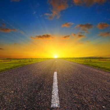 gün batımında yeşil çayır arasında asfalt yol