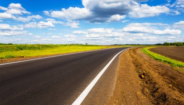 Asfalt yol açmak mavi bir bulutlu gökyüzü altında