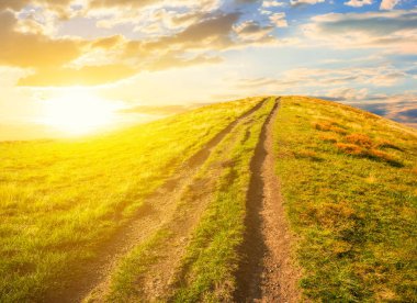 gün batımında küçük yol ile yeşil tepe
