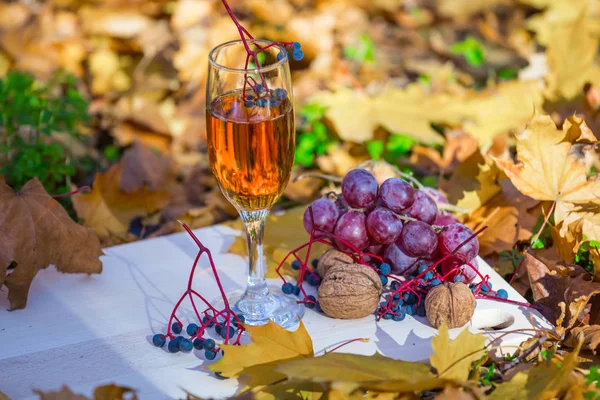 white wine glass on a desk among a red dry leaves