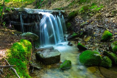 güzel closeup şelale su tarafından bir yosun kaplı taşlar arasında düşen dağ Nehri üzerinde
