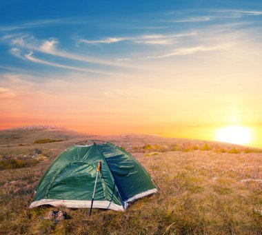 gün batımında otlak arasında yeşil turistik çadır kalmak