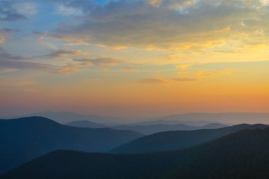 bulutlu gökyüzü altında sabahın erken saatlerinde bir sis dağ zincirleri