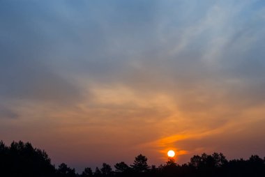 Bir orman silueti üzerinde dramatik kırmızı gün batımı, akşam gökyüzü arkaplanı