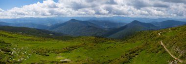 Bulutlu gökyüzünün altındaki yeşil dağlar, geniş panoramik yaz dağ yolculuğu arka planı