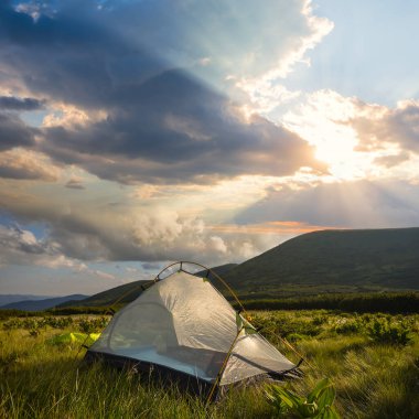 Gün batımında bir dağda turistik kamp, açık hava seyahat sahnesi.
