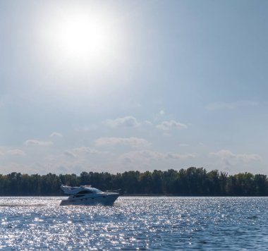 Motorlu yat, sıcak güneşli bir günde, bir gölde dalgaların üzerinde yüzer. Yaz tatili sahnesi.