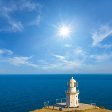 Yalnız beyaz deniz feneri yaz güneşli bir günde deniz pelerininde kalır.