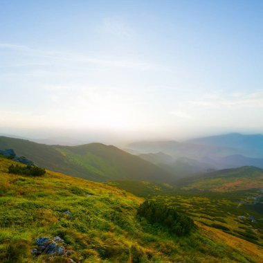 Güneş doğarken mavi sisli yeşil dağ vadisi, sabahın erken saatlerinde yeşil dağ