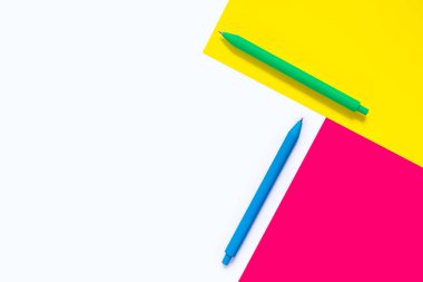 Beyaz zemin üzerinde pembe ve sarı elementlerle izole edilmiş renkli kalemler. Soyut tasarım. Minimalist geometrik stil. Düz yatıyordu. Kopyalama alanı olan. Çalışma ve eğitim kavramı.