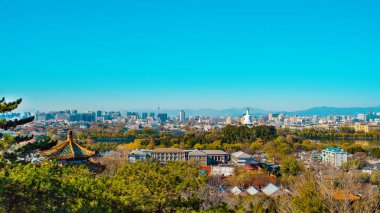 Jingshan Park 'taki gözlem güvertesinden Pekin şehrinin muhteşem manzarası. Beihai Park ve Beyaz Pagoda manzarası. Asya, Çin, Pekin. Çarpıcı bir şehir manzarası. Güneşli bir gün, açık mavi gökyüzü. Panorama görünümü.