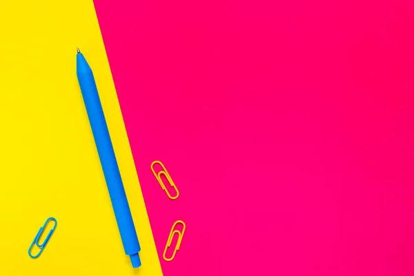 Pembe sarı arka planda mavi kalem. Ofis okul malzemeleri. Minimalist düzlük. Kopyalama. İş ve eğitim kavramı. Yakın görünüm.